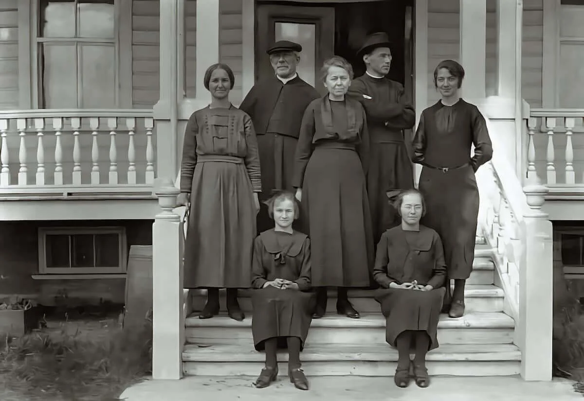Mgr Labrie, le Père Ledoré et plusieurs femmes et jeunes filles devant une maison